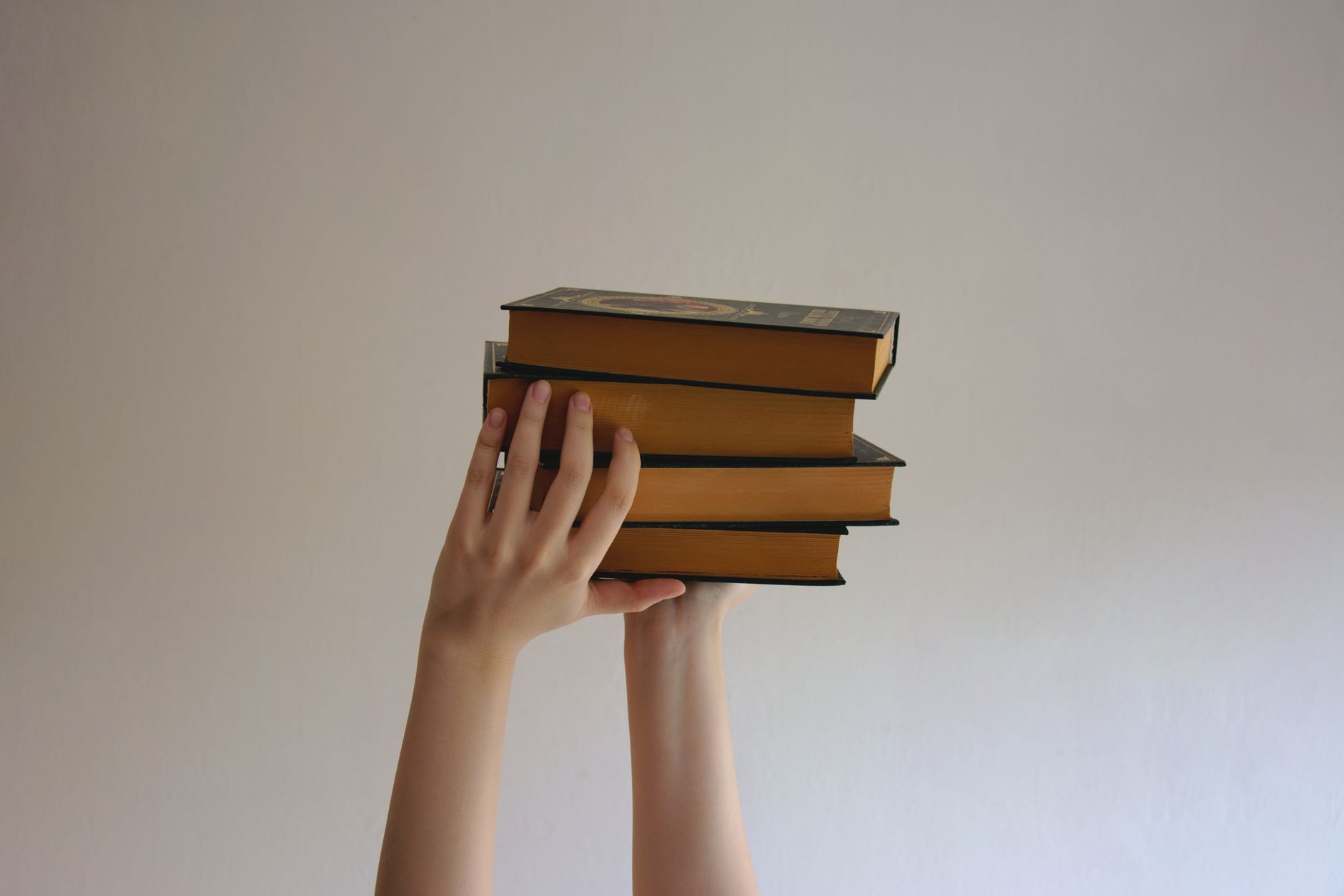 person holding a stack of hardbound books